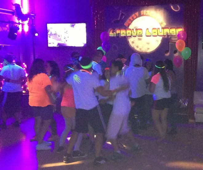People dancing energetically at a lively nightclub with colorful lights.
