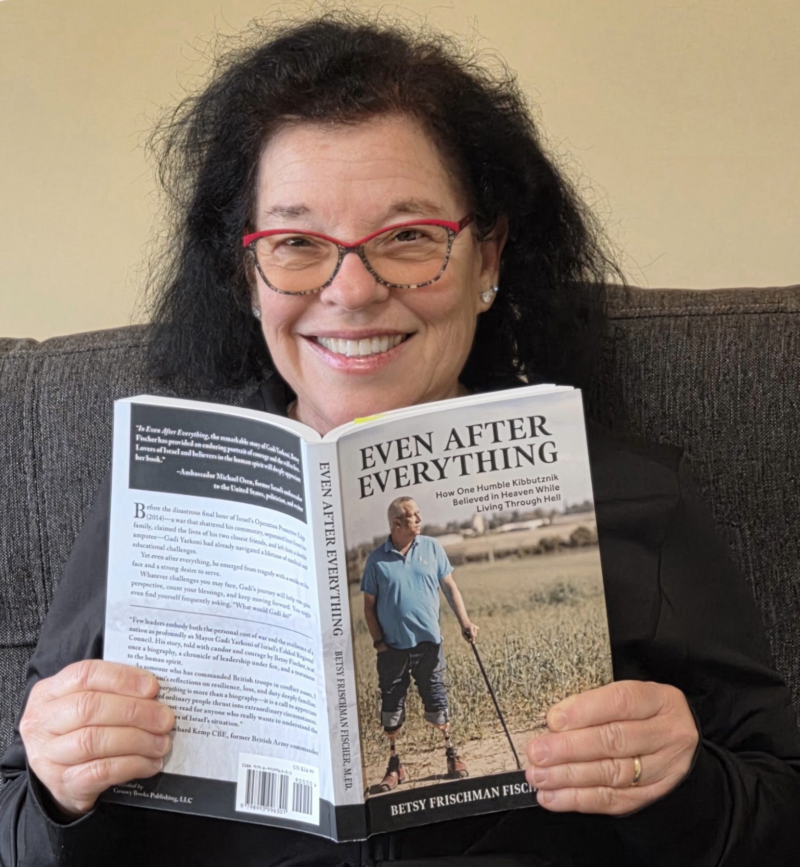 Woman smiling, holding an open book and a magazine titled "Even After Everything."