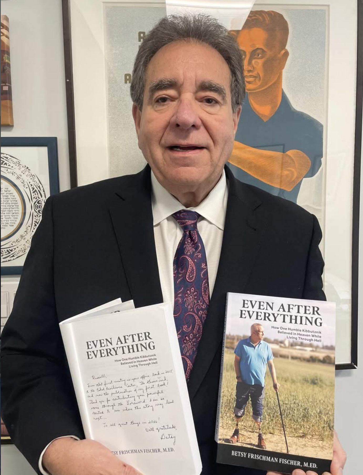 Man holding two copies of the book 'Even After Everything.'